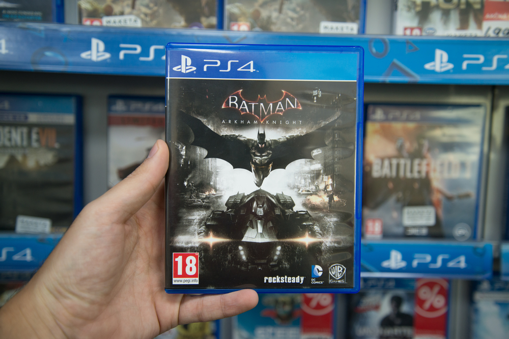 Man holding Batman Arkham Knight videogame on Sony Playstation 4 console in store